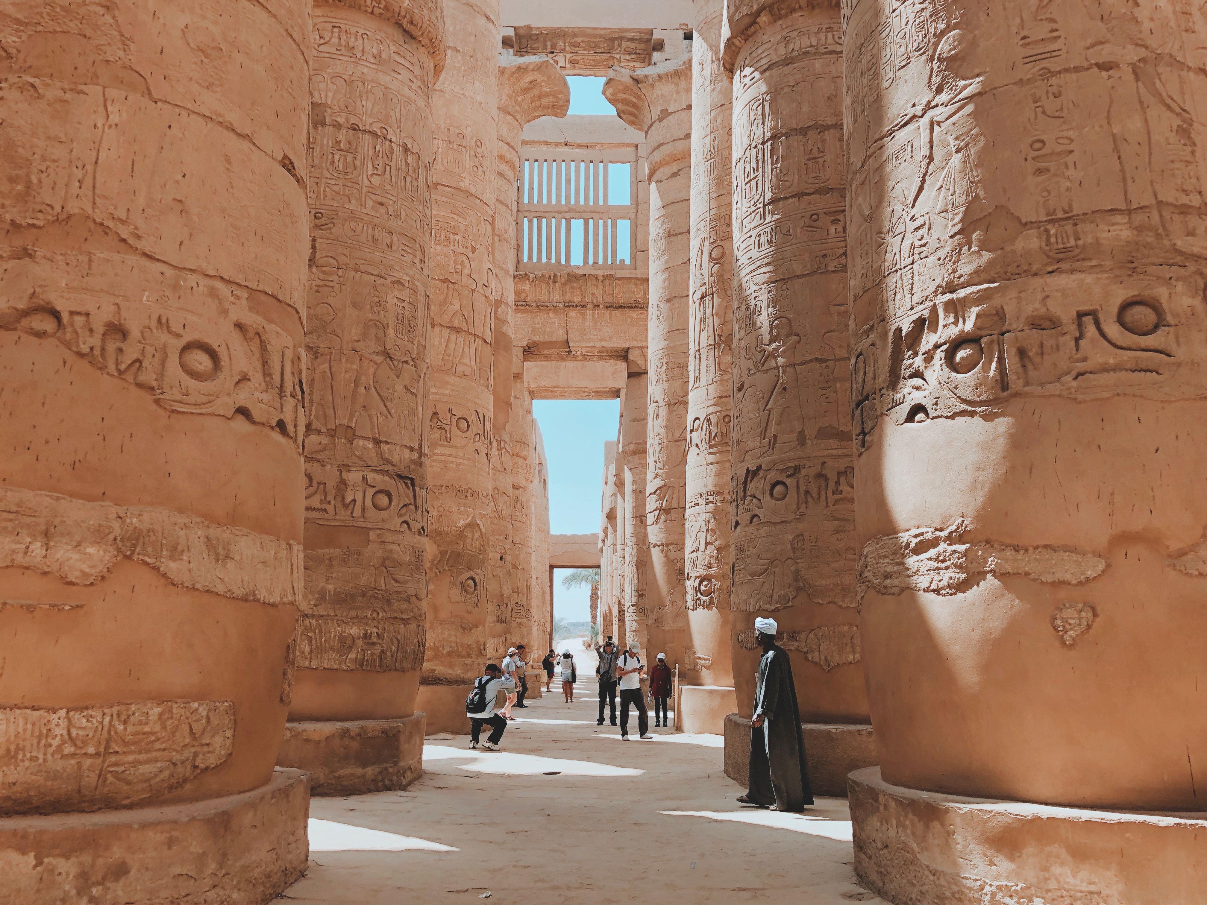 People walking under massive pillars with heiroglyphs in Egypt